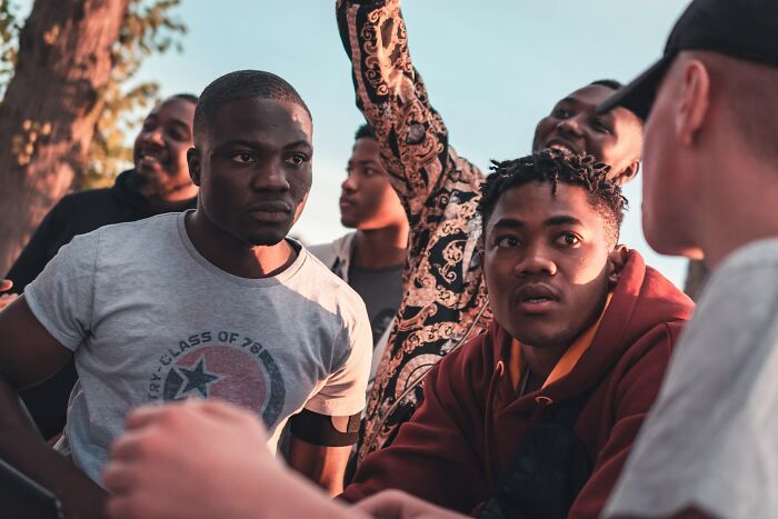 Group of young men in serious discussion illustrating innocent people blamed by police in a tense outdoor scene