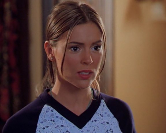 Alyssa Milano speaking about her decision to remove breast implants in a candid indoor setting.