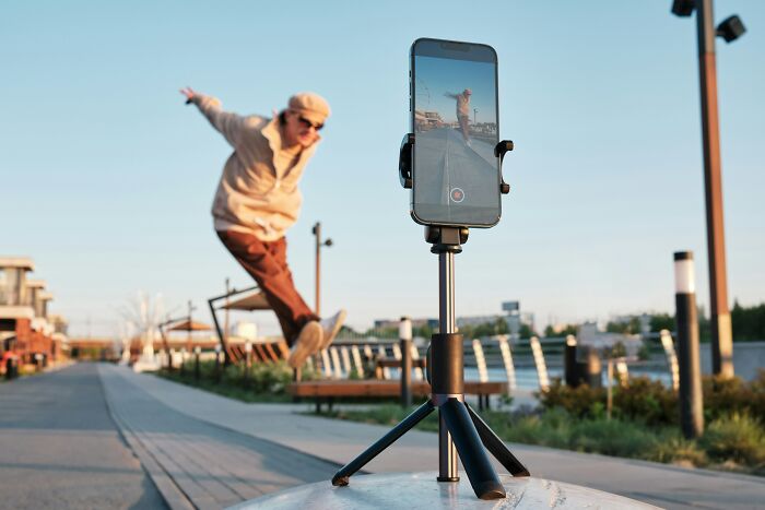 Young person performing a viral TikTok trend outdoors, captured on smartphone mounted on tripod during golden hour.