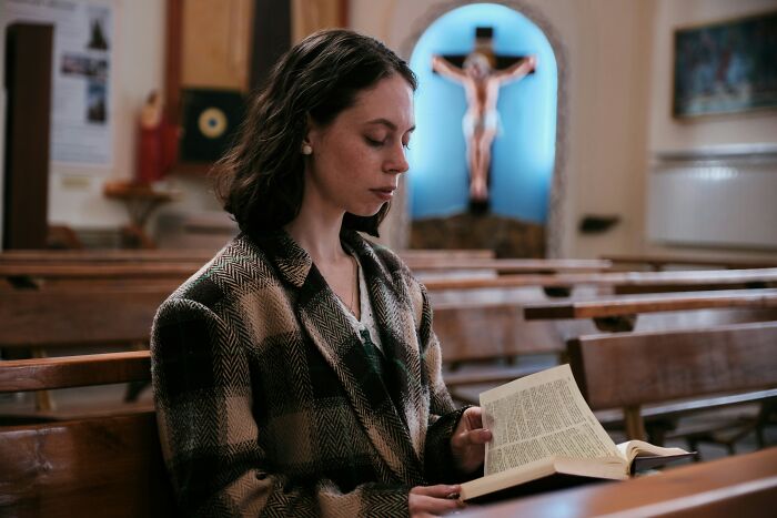 Woman sitting in a church pew, reading a book thoughtfully, illustrating dealbreakers in relationships from women's perspectives.