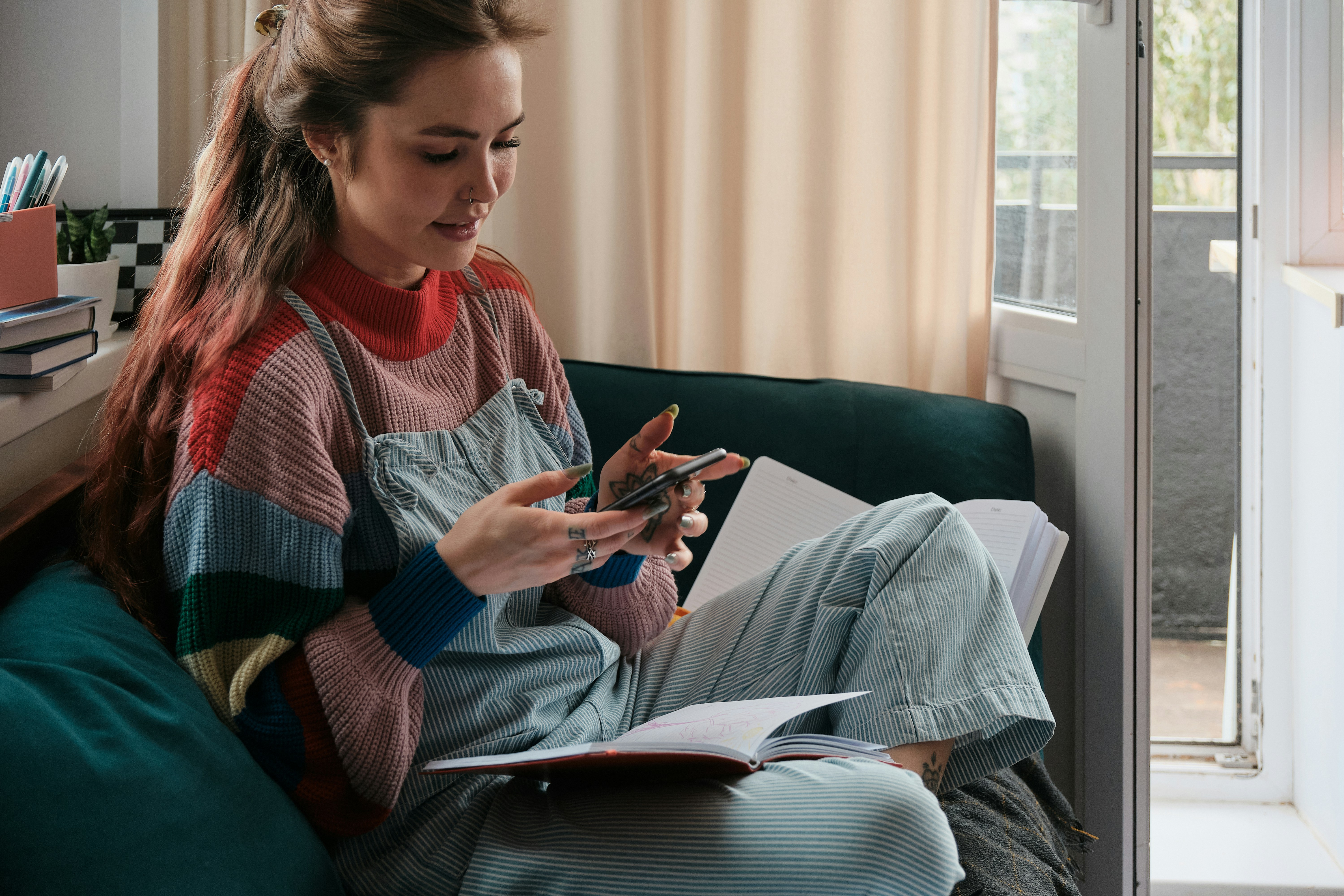 Young woman sitting on a sofa with an open notebook using a phone, illustrating roommate mortgage affordability regrets.