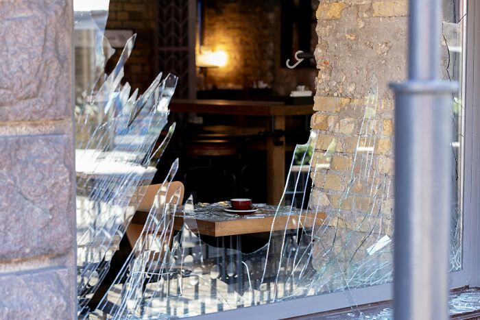Broken glass window of a café, showing damage possibly linked to incidents where innocent people got blamed by police.