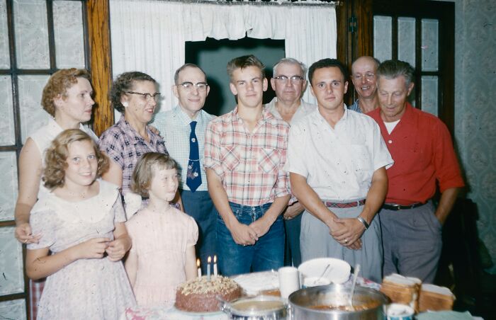 Vintage family gathered around birthday cake indoors, illustrating shocking family secrets revealed by 33 people.