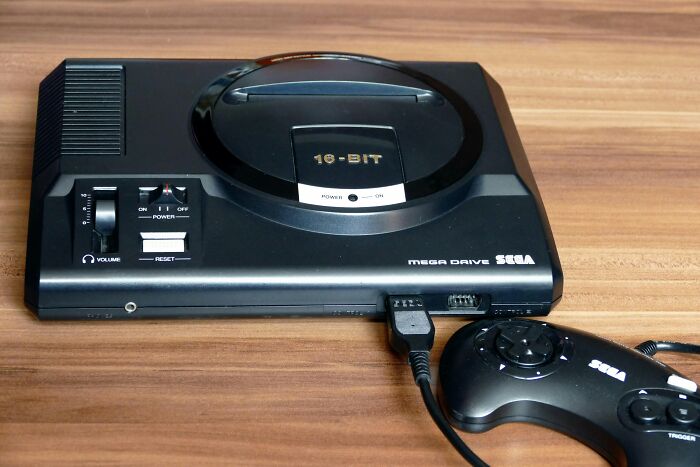 Vintage toys worth fortune Sega Mega Drive 16-bit console with controller on a wooden surface.