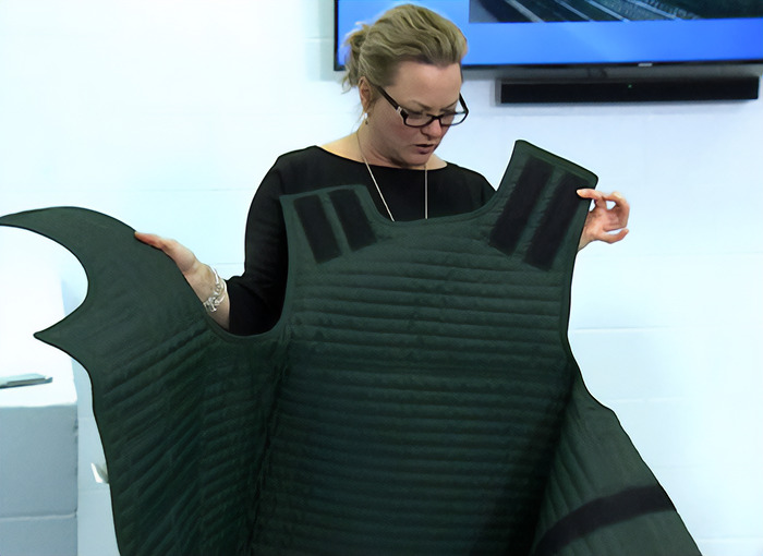 Woman in courtroom holding up a protective vest as people notice an eerie detail related to Tyler Robinson court case