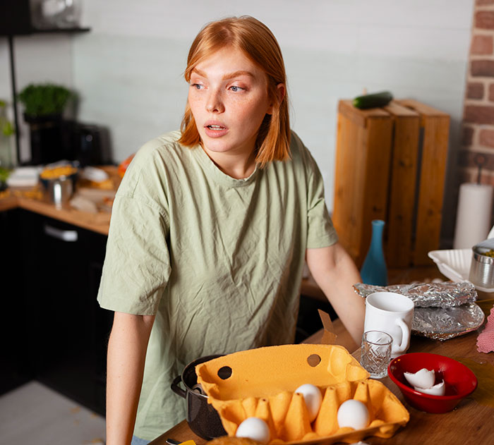 Woman looking stressed in a kitchen with eggs and cooking items, reflecting a husband flipping out while watching kids. Woman looking stressed in a kitchen with eggs and cooking items, reflecting a husband flipping out while watching kids.