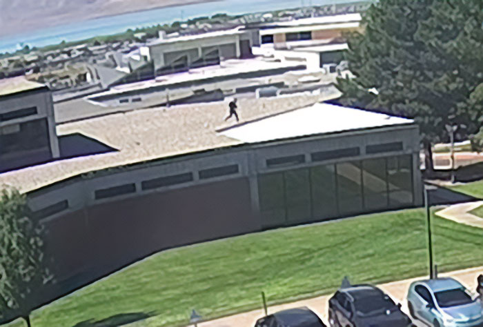 Bearded man seen on rooftop cheering and looking back during crowd event linked to Charlie Kirk attack.