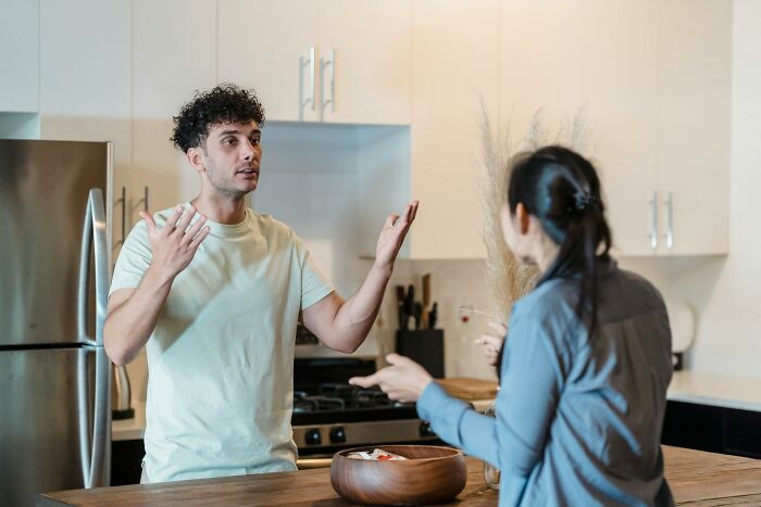 Dad and mom having a tense conversation in kitchen after dad forgets to change diaper and feed baby son.