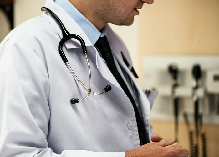 Doctor with stethoscope wearing white coat examining patient, symbolizing dangerous sign on Beckham's body health concerns.