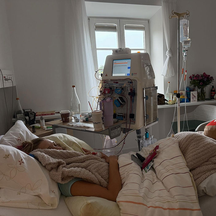 Patient Bella resting in hospital bed receiving dialysis treatment with medical equipment and IV drip in a softly lit room.