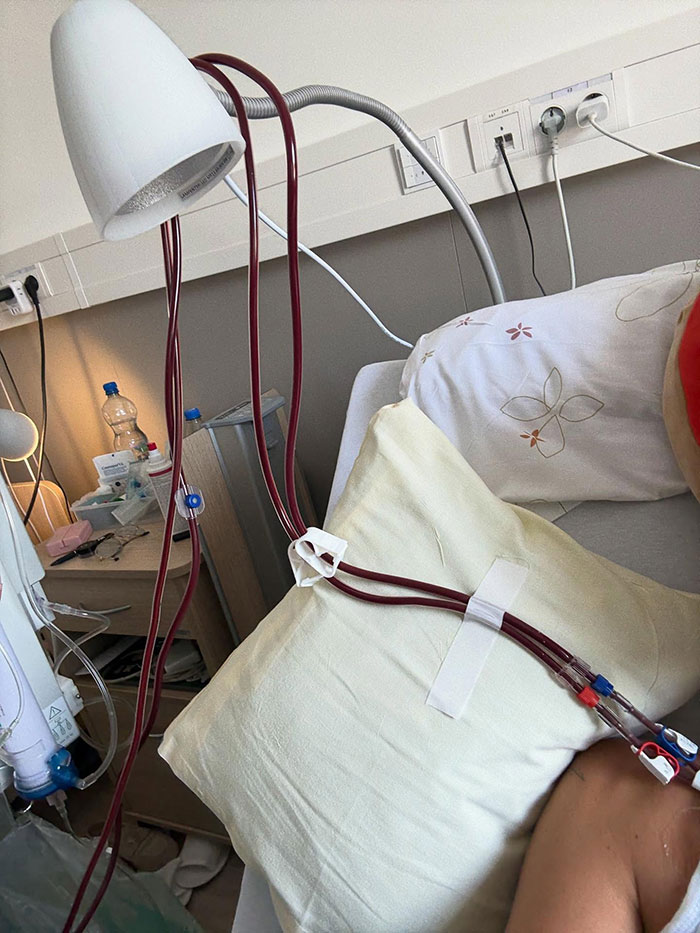 Hospital scene showing medical tubes attached to a patient lying on a bed with pillows and medical equipment nearby