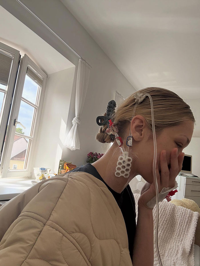 Bella Hadid in a hospital room with medical tubing attached, showing visible signs of illness and recovery.