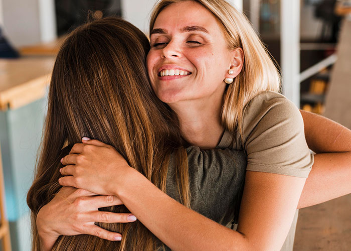 Two women hugging indoors showing friendship and trust, highlighting privacy concerns and cutting off a long-term friend.