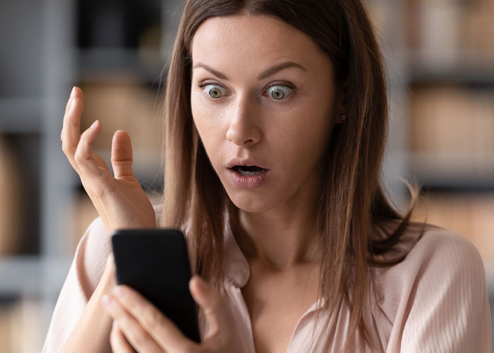 Woman shocked and troubled as she looks at her phone, feeling her privacy was violated by a close friend.