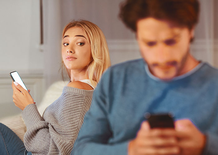 Woman looking suspiciously at friend while both using phones, highlighting concerns about privacy violation in friendship.