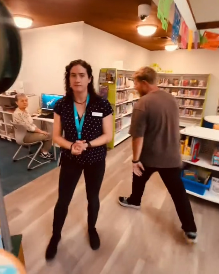 Library staff and visitors inside a library as a man walks away during a confrontation involving racial slur.