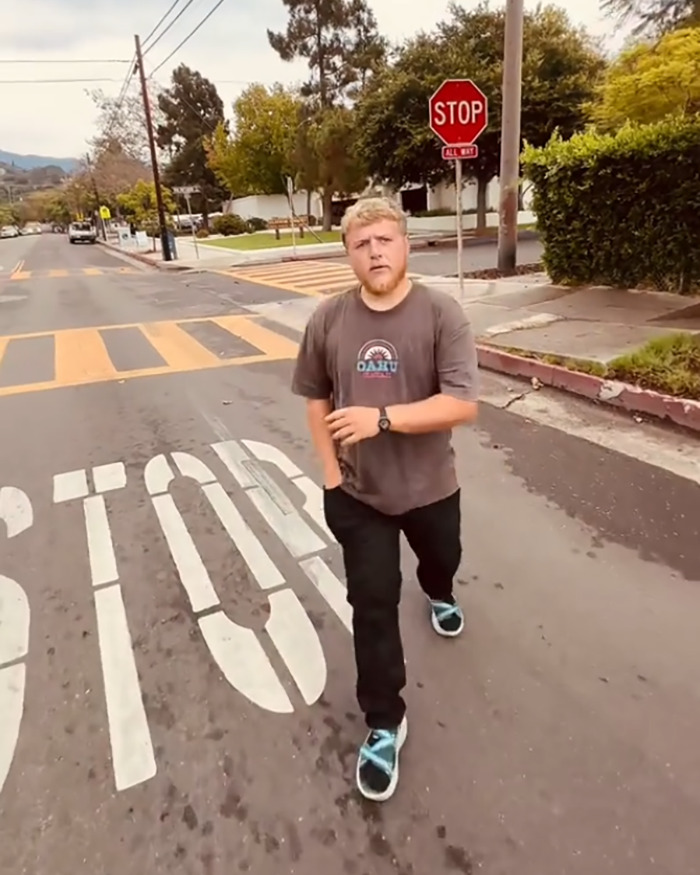 White man walking away on street near stop sign during confrontation over racial slur at library in viral video.