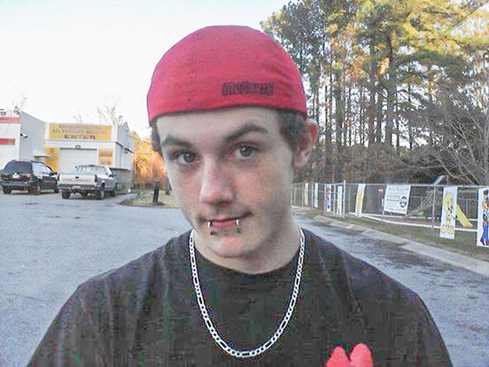 Young man with lip piercings and red cap in outdoor setting, related to major breakthrough in cold case of boy investigation.