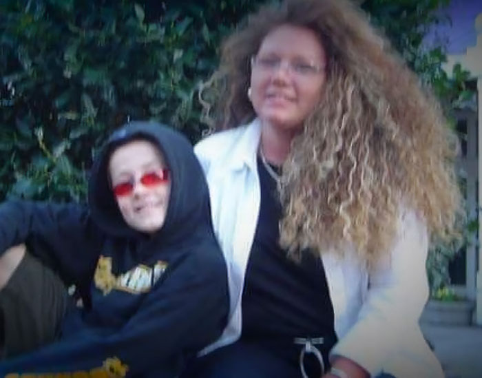 Two people sitting outdoors, with one wearing a hoodie and red glasses, related to major breakthrough in cold case of boy.