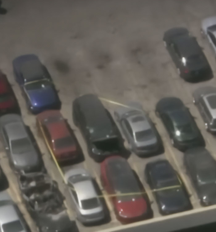 Aerial view of a parking lot with several cars and yellow police tape marking a crime scene connected to wild findings.