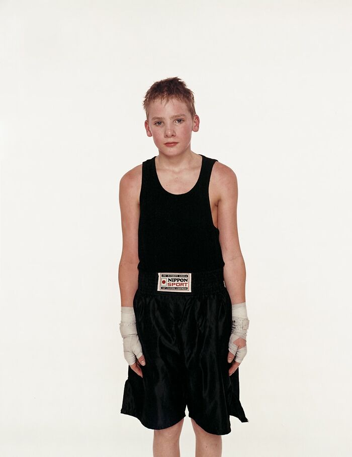 Young boxer in black sportswear posing before his first match with a serious expression on a plain white background.