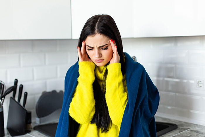 Young woman in yellow sweater feeling stressed after finding hidden device planted by boyfriend in closet prank