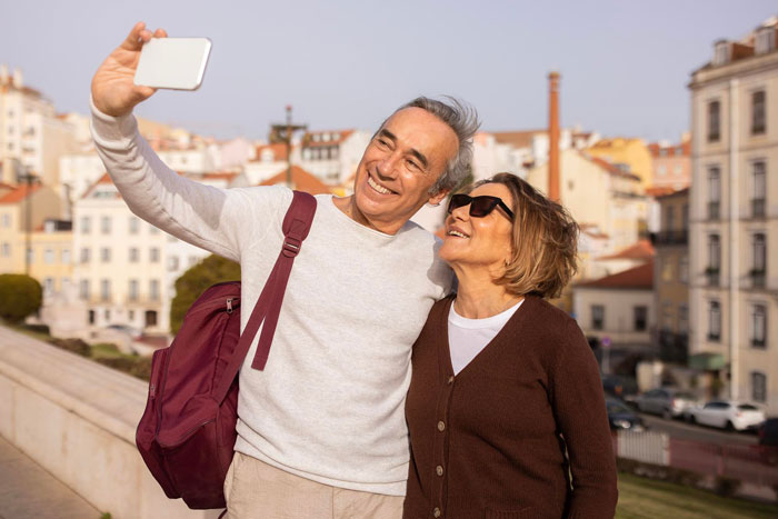 Middle-aged couple taking a selfie outdoors, smiling and enjoying the moment, relating to breaking up over photograph.
