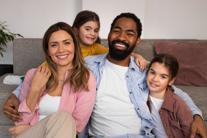 Smiling family including brother and daughter sitting closely together in a cozy living room setting showing strong family drama bonds