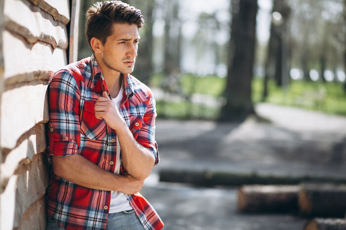 Young man in a red plaid shirt looking anxious and thoughtful outdoors, depicting people saw scary creepy situations.