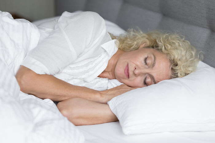 Woman peacefully sleeping in bed, illustrating quiet moments people would never admit in real life.