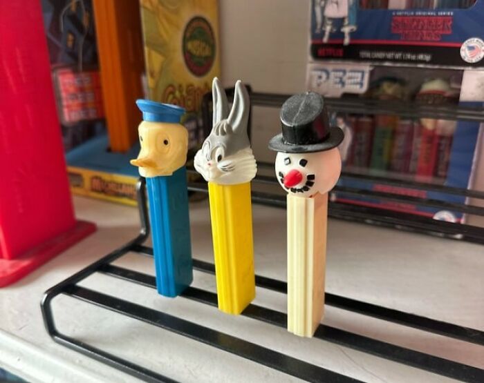 Three vintage toys worth fortune collectible PEZ dispensers featuring duck, rabbit, and snowman characters on a display rack.