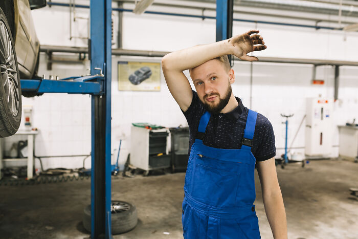 Mechanic wiping sweat in a garage, symbolizing stress related to darkest family secrets found out.