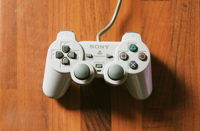 Sony PlayStation controller on wooden surface, representing bold decisions with massive impact in technology and gaming.