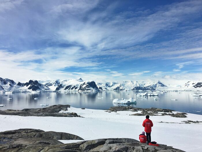 Two people in red jackets overlooking icy mountains and water, symbolizing bold decisions with massive global impact.