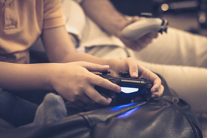 Two people holding video game controllers, focused on playing, illustrating catfish stories and online interactions.