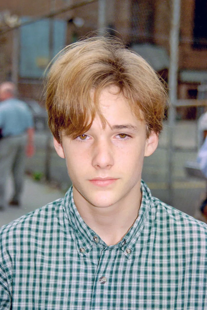 Young male child star with light brown hair wearing a green checkered shirt in an outdoor urban setting