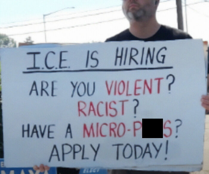 Person holding a sign with a satirical message about I.C.E. hiring, reflecting chaotic good actions in protests.