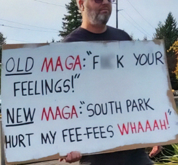 Man holding a sign with a humorous message reflecting chaotic good actions in a public outdoor setting.