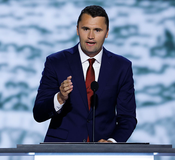 Man speaking at podium in a dark suit and red tie as witnesses describe horrific last moments of Charlie Kirk. Man speaking at podium in a dark suit and red tie as witnesses describe horrific last moments of Charlie Kirk.