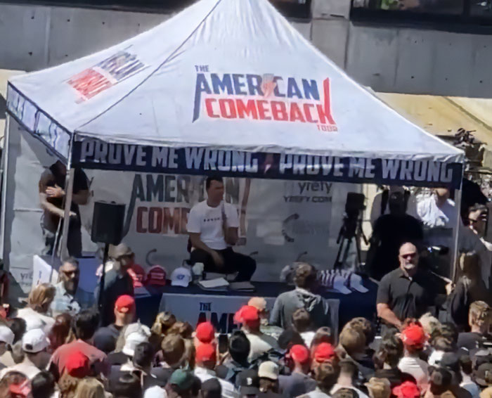 Crowd gathered under a tent at an event discussing Iryna Zarutska and Charlie Kirk's final post after a brutal crime.