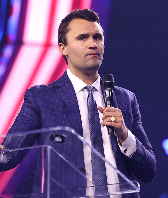 Man in a blue pinstripe suit speaking at a podium with a microphone, related to Amanda Seyfried and Charlie Kirk controversy. Man in a blue pinstripe suit speaking at a podium with a microphone, related to Amanda Seyfried and Charlie Kirk controversy.