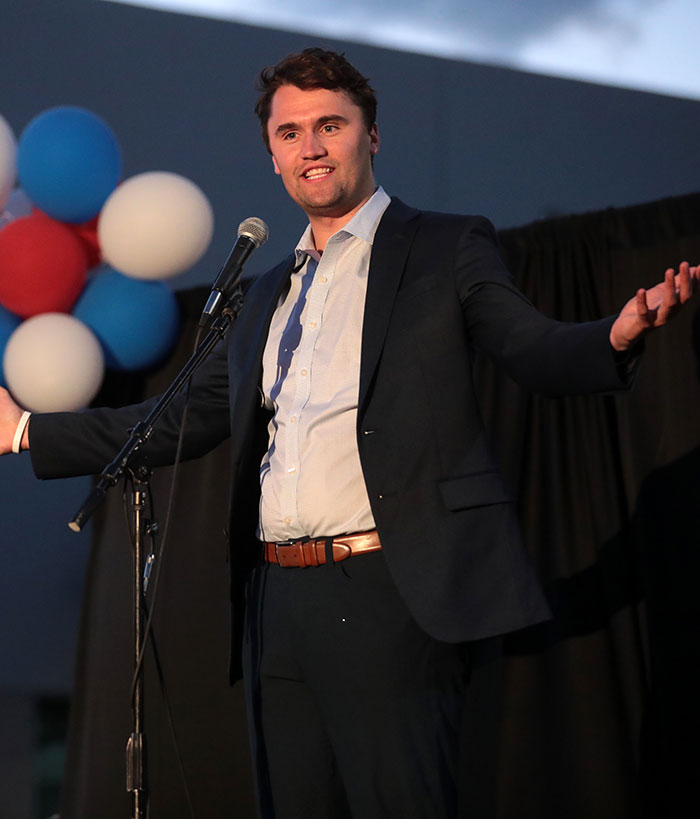 Charlie Kirk speaking at an event with balloons in the background, expressing a passionate gesture on stage. Charlie Kirk speaking at an event with balloons in the background, expressing a passionate gesture on stage.