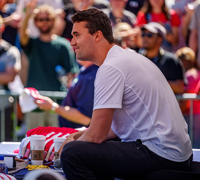 Man sitting at an outdoor event, crowds in background, related to witnesses describing last moments of Charlie Kirk. Man sitting at an outdoor event, crowds in background, related to witnesses describing last moments of Charlie Kirk.