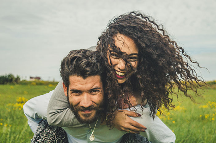 Happy couple outdoors showing love and laughter despite future MIL branding bride-to-be stupid in a field.