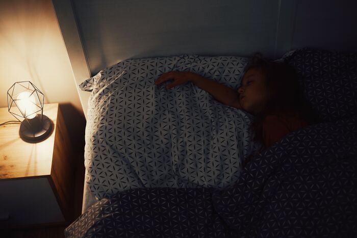 Person sleeping in bed at night with a bedside lamp, symbolizing innocence and wrongful police blame cases.