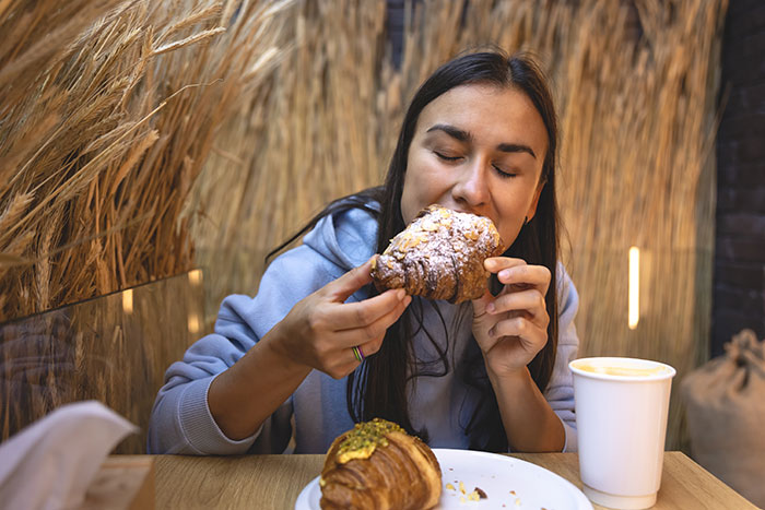 Woman enjoying a croissant and coffee, illustrating unusual and ridiculous cures offered to chronically ill people.