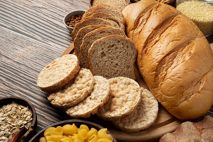 Assortment of bread, rice cakes, and pasta displayed on a wooden surface representing ridiculous cures offered to chronically ill.