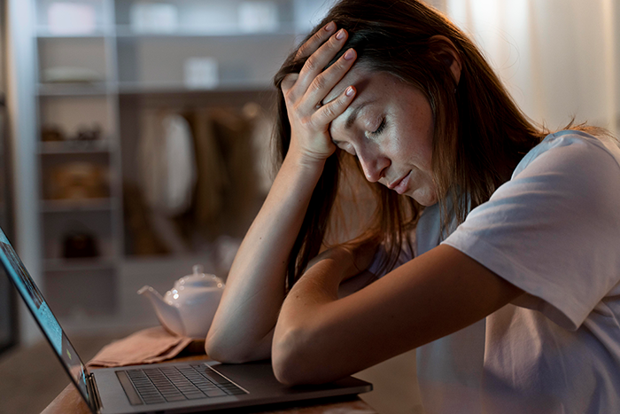Stressed woman with hand on forehead sitting at laptop, illustrating long-distance romance cheating and rumor scandal. Stressed woman with hand on forehead sitting at laptop, illustrating long-distance romance cheating and rumor scandal.