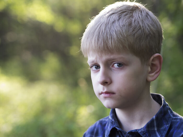 Young boy with blond hair looking worried outdoors, capturing people saw scary creepy situations in a natural setting.