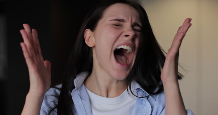 Young woman reacting in fear, raising hands and screaming, capturing people who saw scary creepy situations.